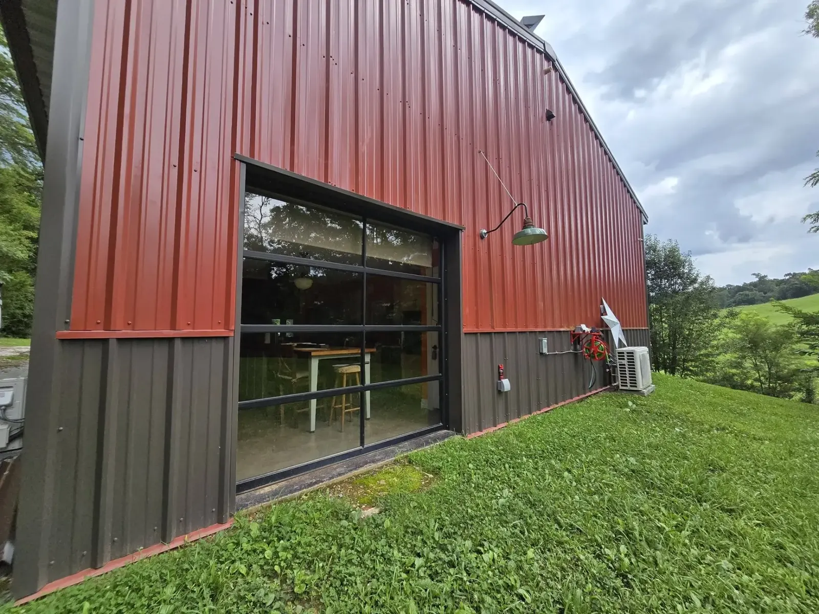 Full-view glass garage door on a red metal shop building