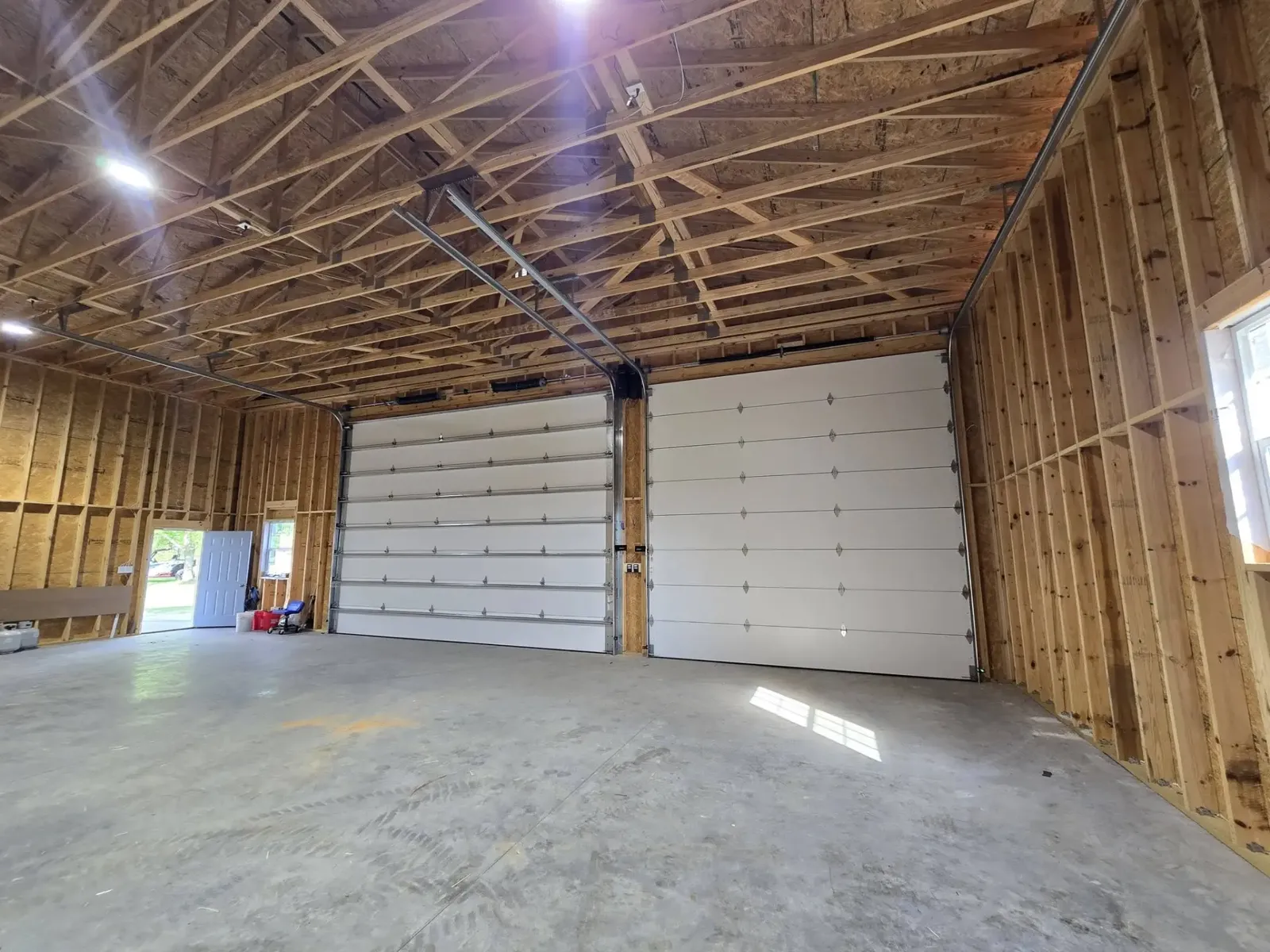 New white garage door installed in a wood-framed pole barn