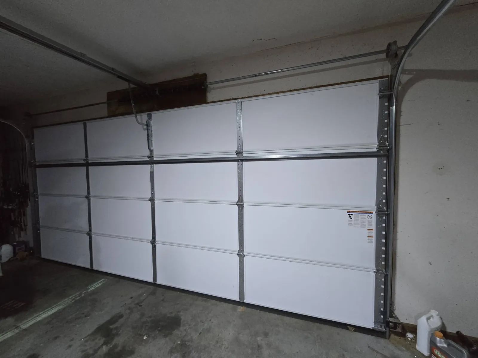 New white flush-panel garage door installed inside a residential garage