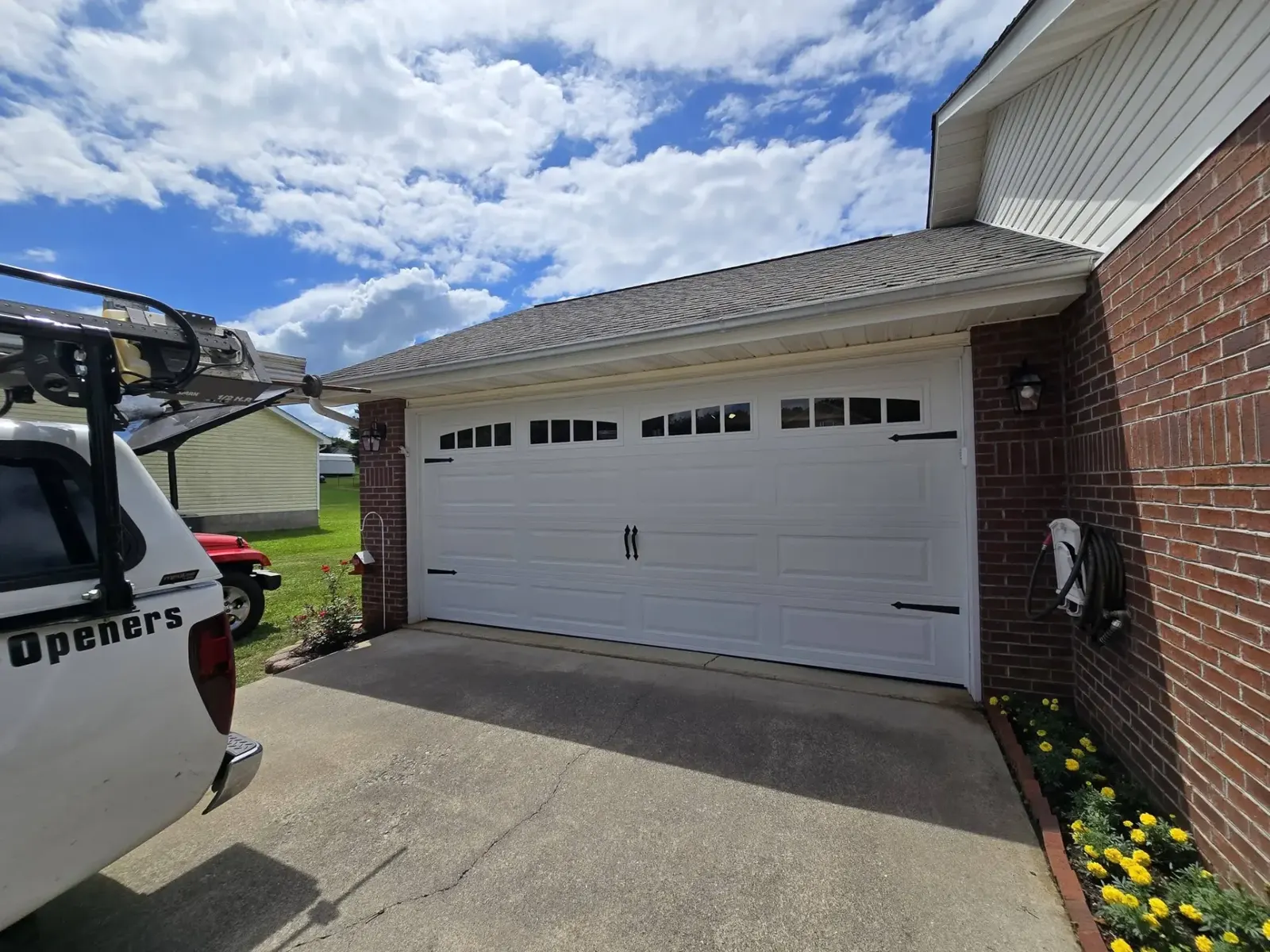New white long-panel garage door installed on a brick home