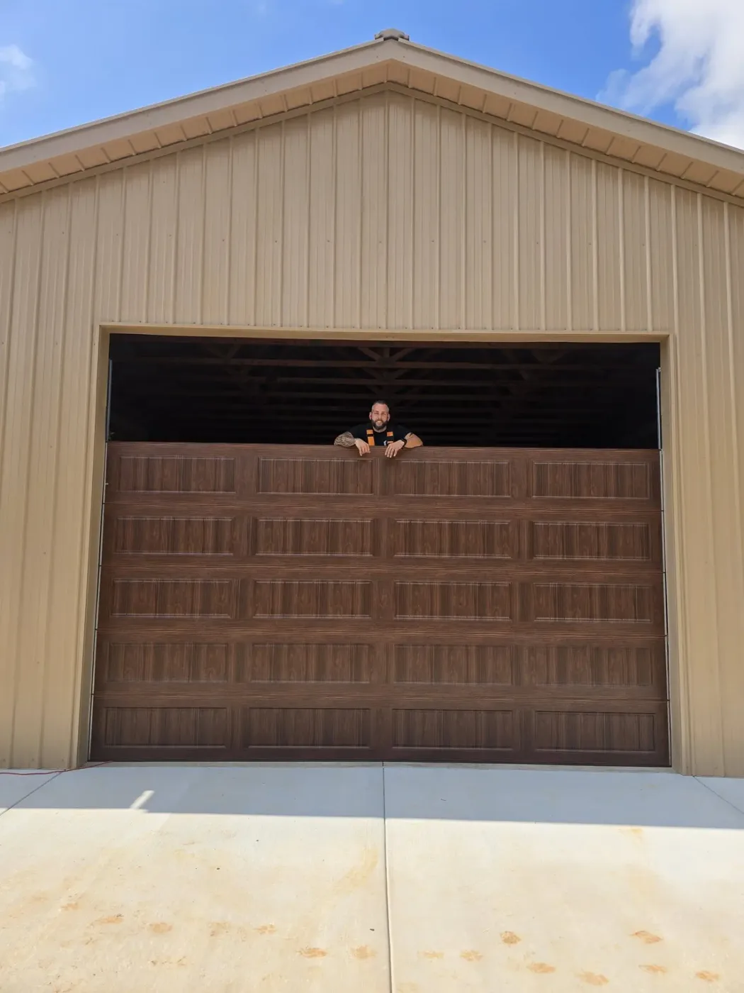 Josh standing behind a newly installed wood-look garage door at a job in Loudon County, Tennessee