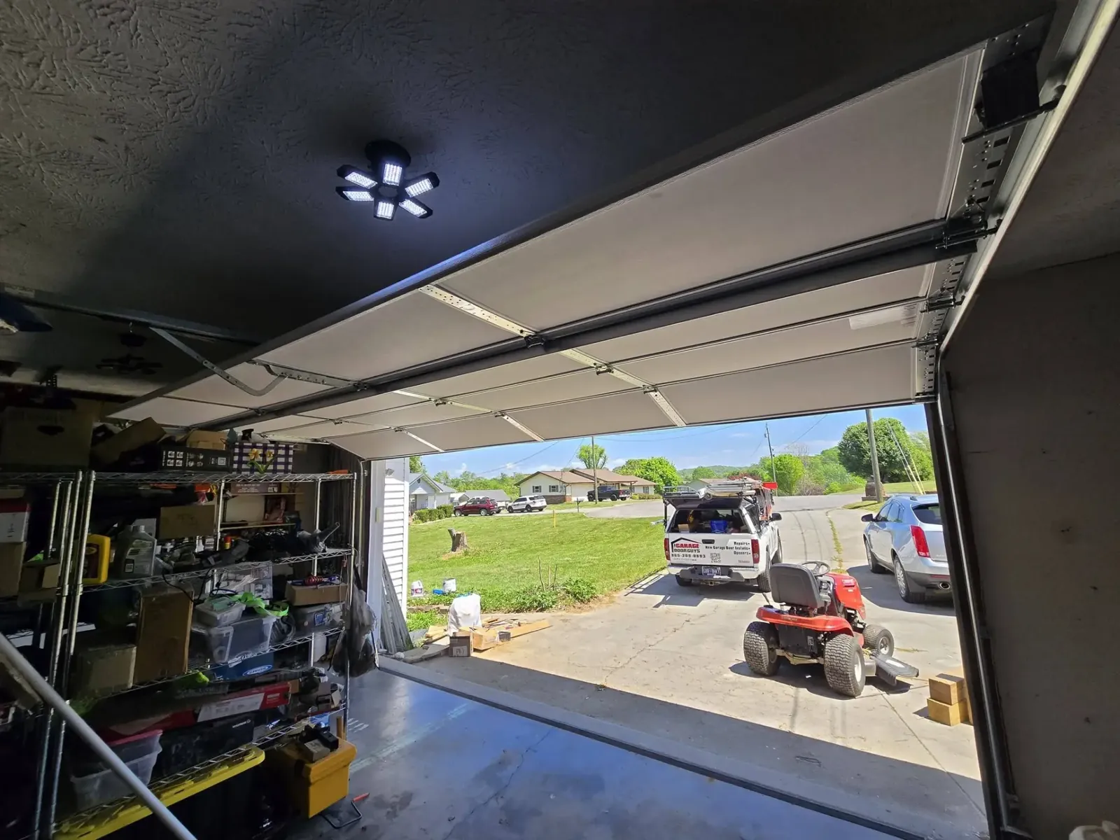 View from inside a garage of a newly installed insulated door with the service truck parked outside