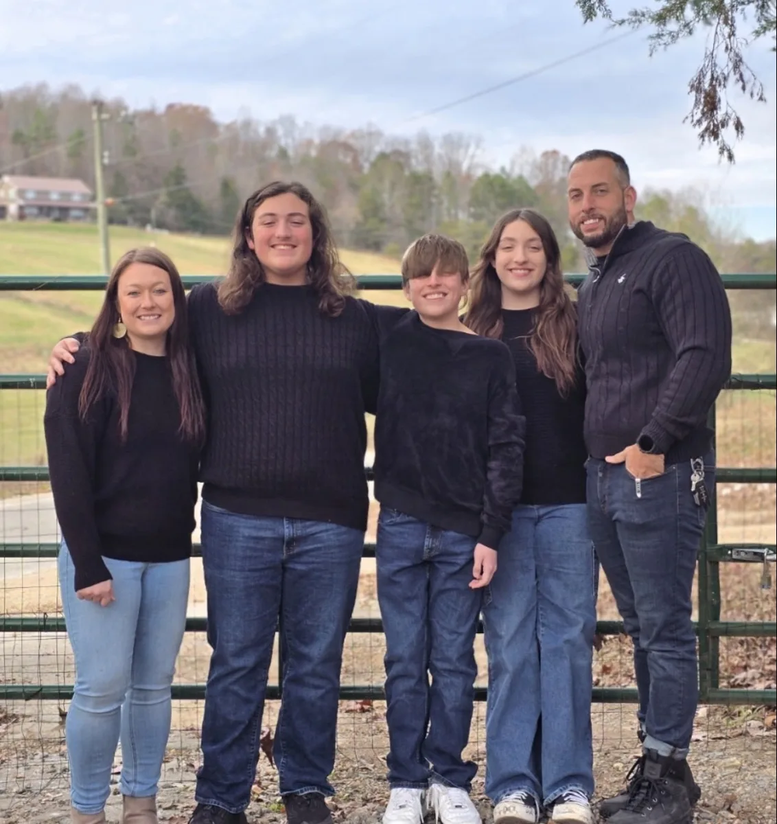Josh with his wife and three children standing by a farm gate in East Tennessee