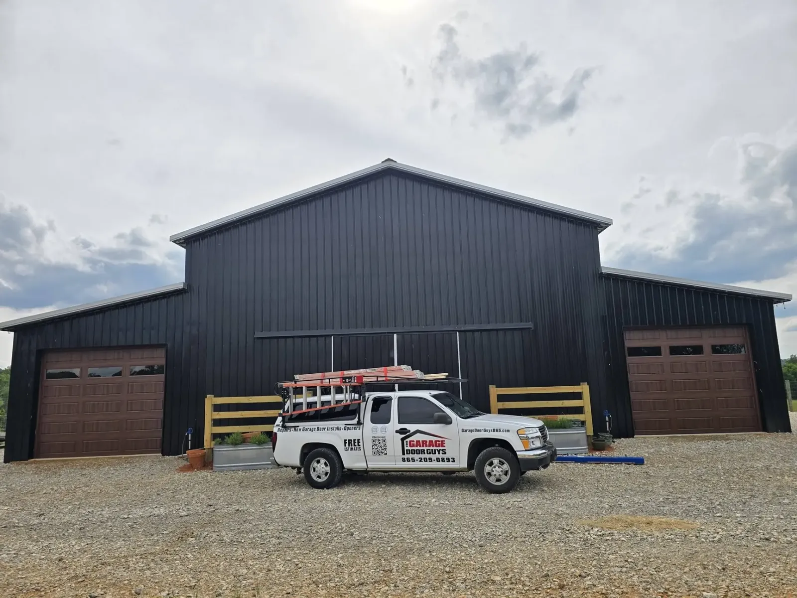 Service truck in front of a black barn with two new wood-look garage doors