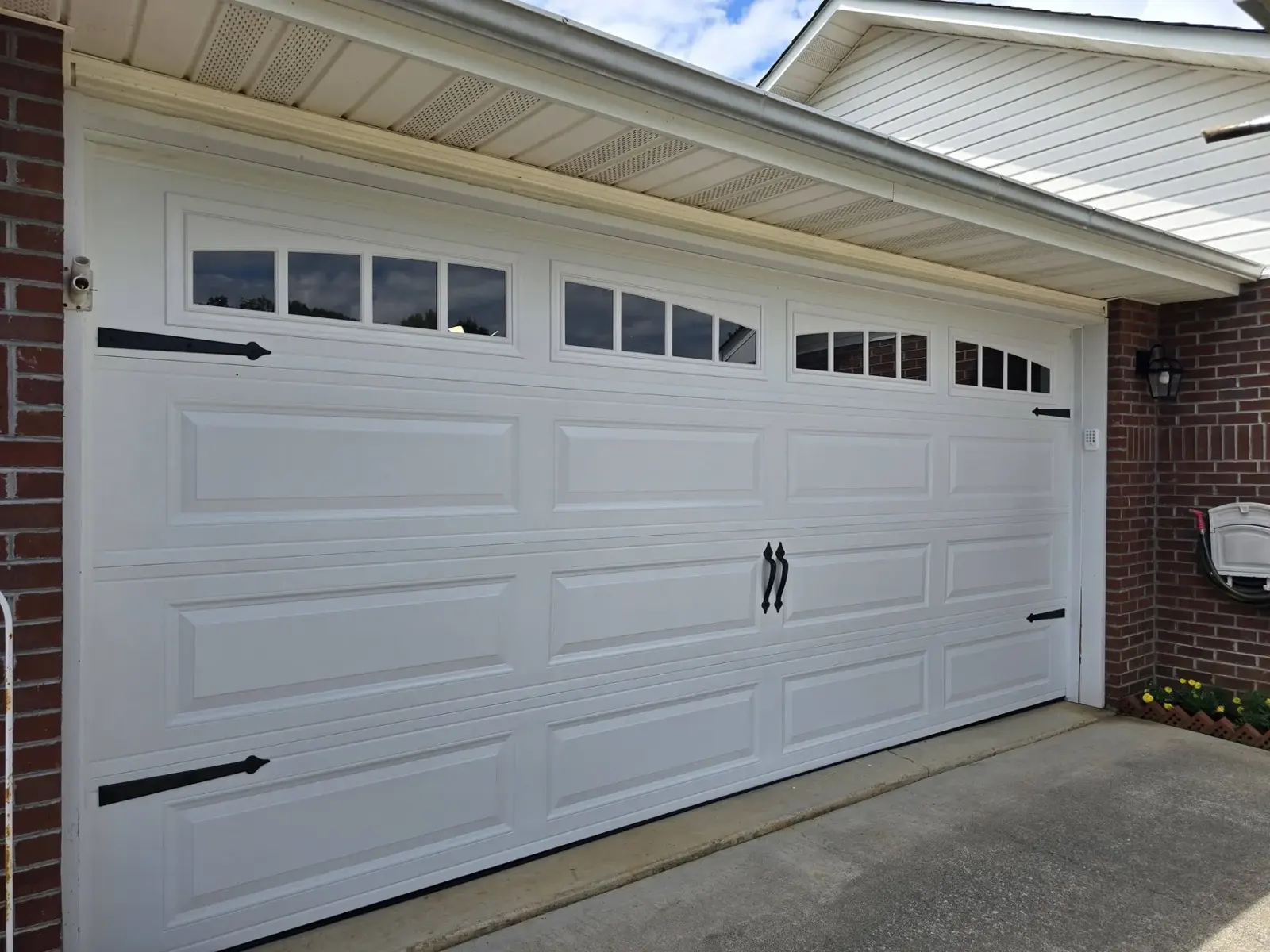 White carriage-style garage door with windows and decorative hardware